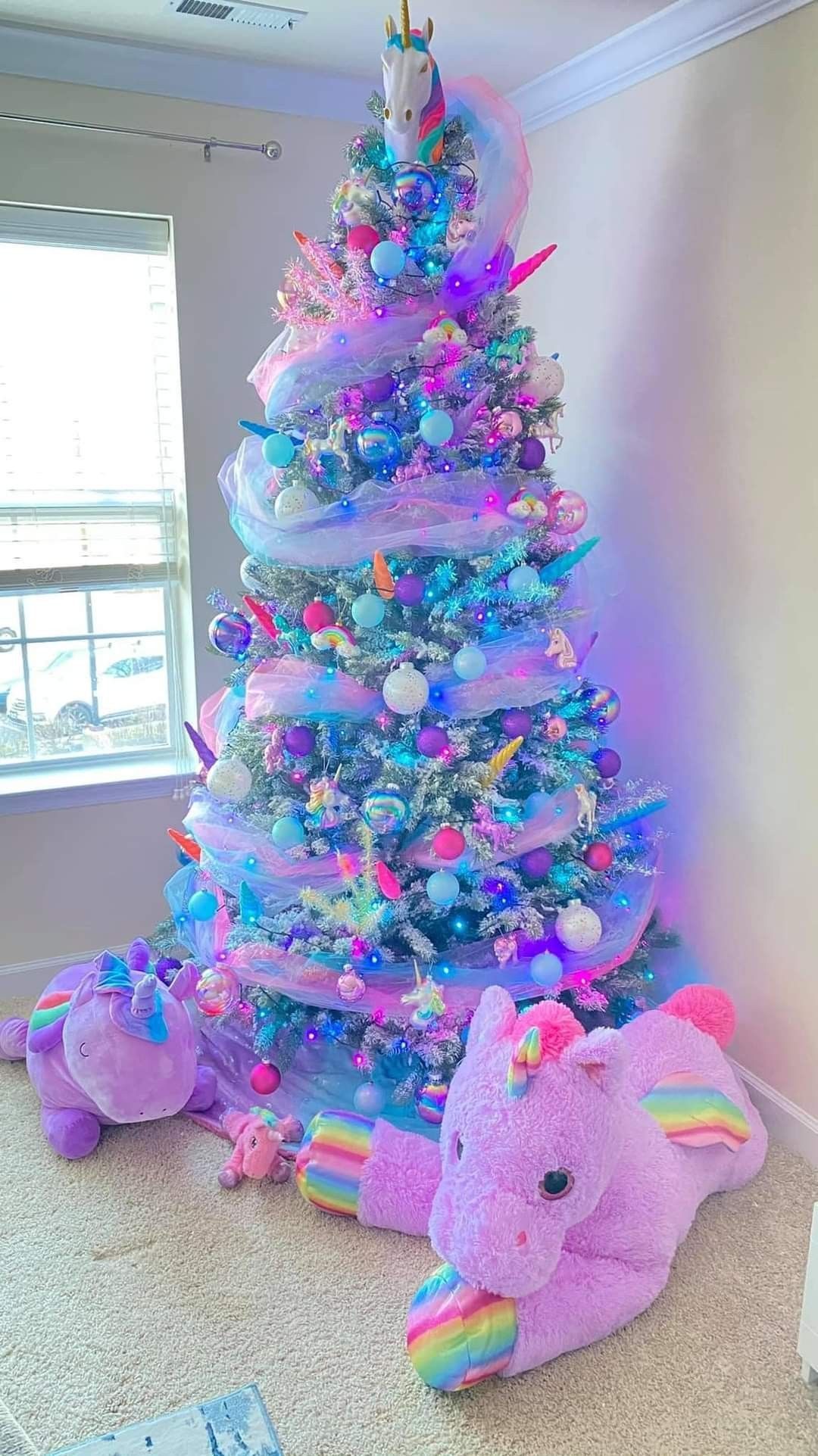 A rainbow unicorn Christmas tree with a mix of colorful ornaments and a rainbow tree topper